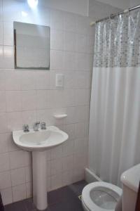Baño blanco con lavabo y aseo en HOSTAL TILIAN en Salta