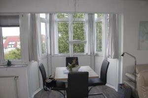 una mesa y sillas en una habitación con ventanas en Grüntal Residenz I Whg 6, en Grömitz