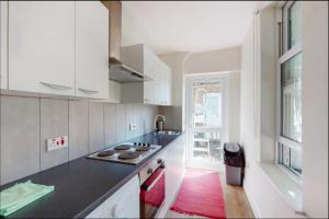 a kitchen with white cabinets and a black counter top at Private self-contained studio close to Hampstead, Golders Green & Camden Town in London