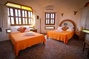 een slaapkamer met 2 bedden met oranje lakens en ramen bij Hotel Gilda in Coyuca