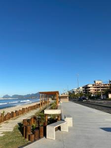 a row of benches on a sidewalk next to the beach at Apartament Piratininga in Niterói