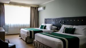 a hotel room with two beds and a window at Ecohotel Talca in Talca