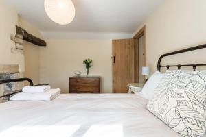 a bedroom with a large white bed and a sink at Lovely Cosy Stone Cottage in Tetbury Cotswolds in Tetbury