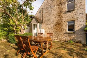 a wooden table and chairs in front of a building at Lovely Cosy Stone Cottage in Tetbury Cotswolds in Tetbury