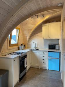 a kitchen with an archway in a tiny house at Owl Glamping Pod in Leighton