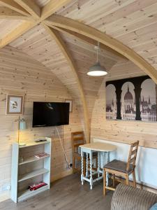 Pokój z drewnianym sufitem, stołem i telewizorem w obiekcie Owl Glamping Pod w mieście Leighton