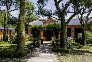 una pasarela frente a una casa con árboles en Pampas del Sur Hotel y Spa de campo en Cañuelas