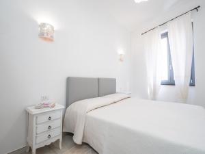 a white bedroom with two beds and a window at Affittacamere Solki in SantʼAntìoco
