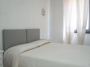 Habitación blanca con cama y ventana en Affittacamere Solki, en SantʼAntìoco