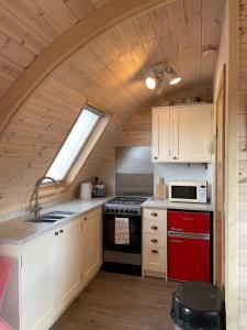 a kitchen with white cabinets and a red stove at Squirrel Glamping Pod in Leighton +9 photos