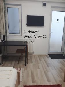 uma sala de estar com uma secretária e uma televisão na parede em Bucharest Wheel View em Bucareste