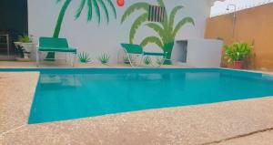 une piscine bleue avec 2 chaises vertes et des plantes dans l'établissement La Case a Mamy, à Nianing