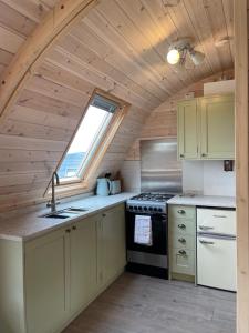 a kitchen with a stove and a window at Rabbit Glamping Pod School House Farm in Leighton