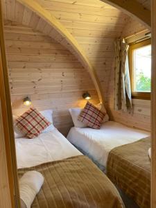 a room with two beds in a log cabin at Rabbit Glamping Pod School House Farm in Leighton