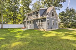 a house on a grassy yard with trees in the background at Sun-Dappled Retreat - Walk to Wickaboag Lake! in West Brookfield