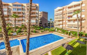 einen Blick über einen Pool mit Palmen und Apartmentgebäuden in der Unterkunft Nice Apartment In Arenales Del Sol With Kitchen in Elche