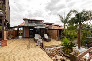 a house with a wooden deck in front of it at Pousada Descanso do Rei - Vista Para o Mar & Melhor Localização da Praia do Rosa in Praia do Rosa