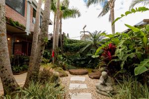 a garden with palm trees and a stone pathway at Pousada Descanso do Rei - Vista Para o Mar & Melhor Localização da Praia do Rosa in Praia do Rosa