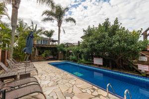 a swimming pool with chairs next to a house at Pousada Descanso do Rei in Praia do Rosa