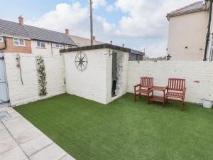 a patio with two chairs and a fence with green grass at 7 Marine Drive in Hartlepool