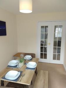 a wooden table with plates and wine glasses on it at Sunningdale homely detached family/contractor 3 bed house in Lincolnshire