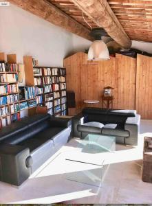 een woonkamer met een zwarte leren bank en boekenplanken bij LASUITE Domaine Bertuli, heated Pool, Aircon in Oppède