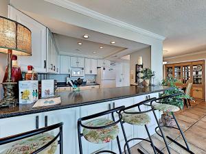 ペンサコーラ・ビーチにあるSabine Yacht & Racquet #5Eのキッチン(白いキャビネット、カウンター、椅子付)