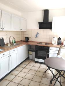 uma cozinha com armários brancos, uma mesa e um lavatório em Südeifel Badem em Badem