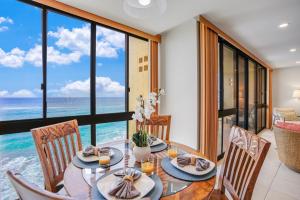 a dining room with a table and chairs with a view of the ocean at Kuhio Shores 410 in Koloa