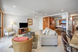 ein Wohnzimmer mit einem Sofa und einem TV in der Unterkunft Kuhio Shores 410 in Koloa
