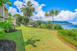 a house next to the water with palm trees at Pali Ke Kua 111 in Princeville