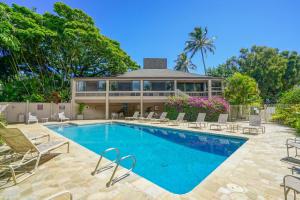 a swimming pool with chairs and a house at Pali Ke Kua 111 in Princeville