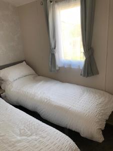 2 Betten in einem Schlafzimmer mit Fenster in der Unterkunft Tranquility No 42 Port Haverigg Marina in Millom