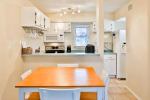 a kitchen with a wooden table and white cabinets at Dockside Destiny in St. Pete Beach