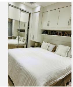 um quarto com uma cama grande com lençóis brancos e almofadas em Apartamento leblon no Rio de Janeiro