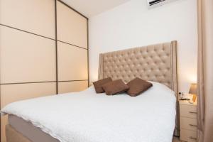 a bedroom with a white bed with two brown pillows at Apartment Odysseus in Tivat