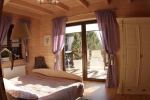 a bedroom with a bed and a window with purple curtains at OSADA JEŻÓWKA in Rąty