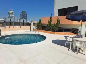 a pool with a table and chairs and an umbrella at Cosmopolitan Praia Flat in Santos