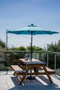 a wooden picnic table with an umbrella on a deck at Coastguard Cottage Cornwall - Sea & Harbour Views in Mevagissey