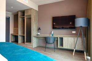 een slaapkamer met een tv en een bureau met een stoel bij H24 Stadthotel Bernau in Bernau bei Berlin