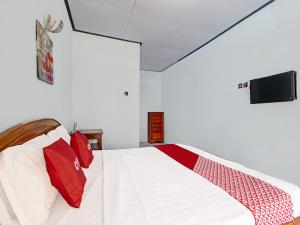 a bedroom with a bed with red pillows and a tv at Capital O 91644 Loka Hause in Salatiga