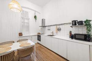 uma cozinha com armários brancos e uma mesa e cadeiras em The BoHo Loft VIE em Viena