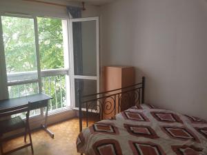 a bedroom with a bed and a desk and a window at une chambre privee entre paris et disneyland in Noisy-le-Grand