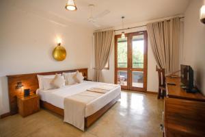 1 dormitorio con 1 cama grande y TV en Kalu's Hideaway Udawalawe, en Udawalawe