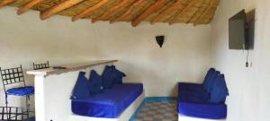 Les Jardins d Amizmiz في أمزميز: غرفة بها كراسي ذات وسائد زرقاء وتلفزيون