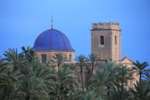 een gebouw met een klokkentoren en een gebouw met palmbomen bij Elche Holidays in Elche