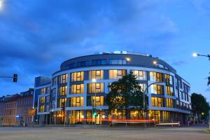 un grand bâtiment avec de nombreuses fenêtres donnant sur une rue de la ville dans l'établissement H24 Stadthotel Bernau, à Bernau bei Berlin