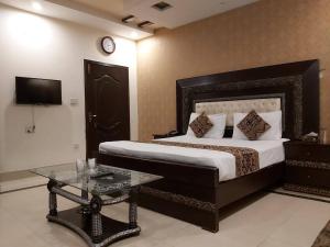 1 dormitorio con cama, mesa y reloj en Hotel Visit Inn One, en Lahore