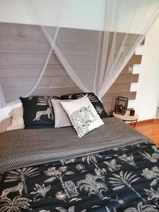 uma cama com lençóis e almofadas preto e branco em Les Bichettes em Mortagne-sur-Sèvre