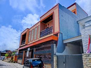 a blue building with a car parked in front of it at OYO 91649 Orange Homestay Makassar in Makassar